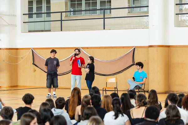 Vista do palco improvisado no pavilhão, com os alunos sentados em frente.