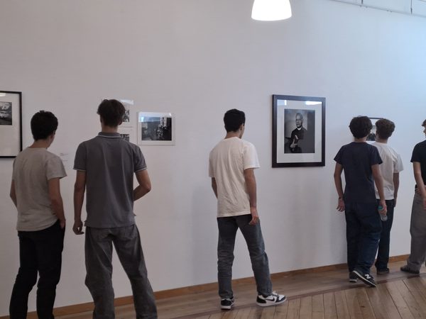 Alunos, de costas, a observar as fotografias expostas numa das paredes da sala.